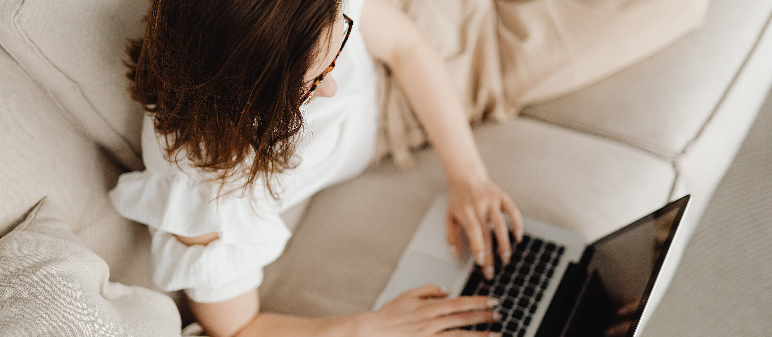 A woman lies on the sofa with her laptop and uses online check-in