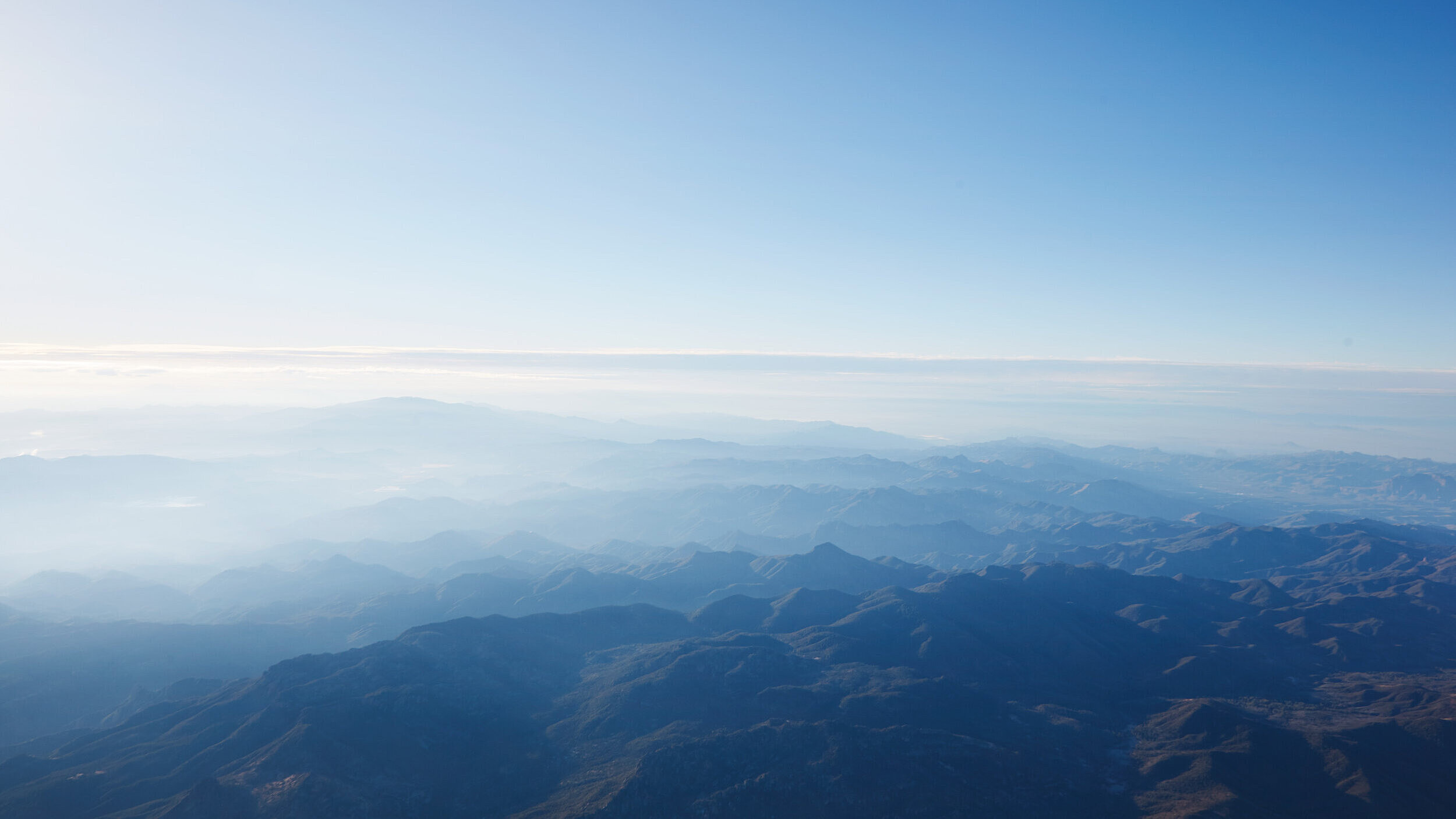View from a plane over a mountainous landscape in the morning mist
