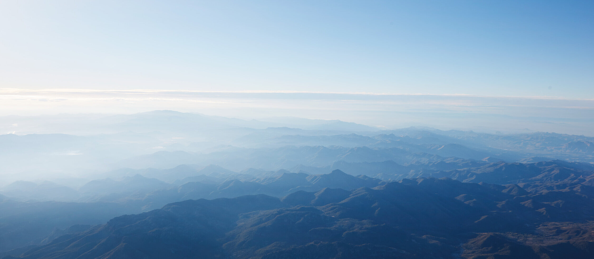 View from a plane over a mountainous landscape in the morning mist