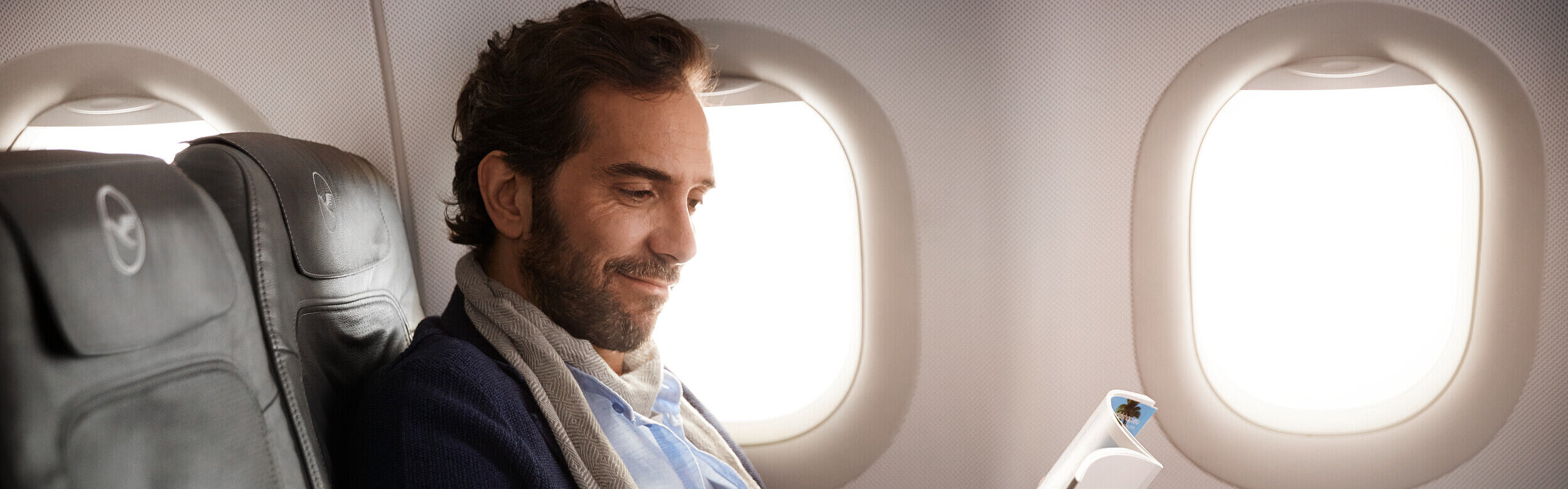 Passagier genießt den Flug in der Businessklasse und liest ein Magazin