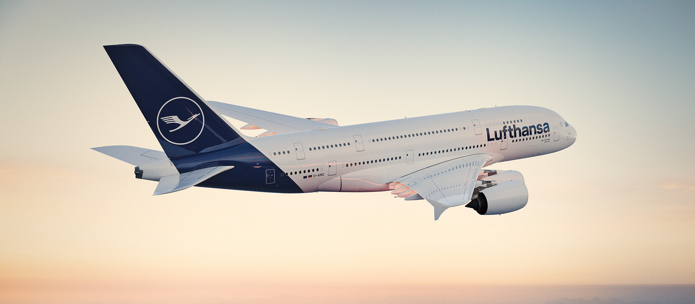 A Lufthansa Airbus A380 in flight over a foggy, mountainous landscape