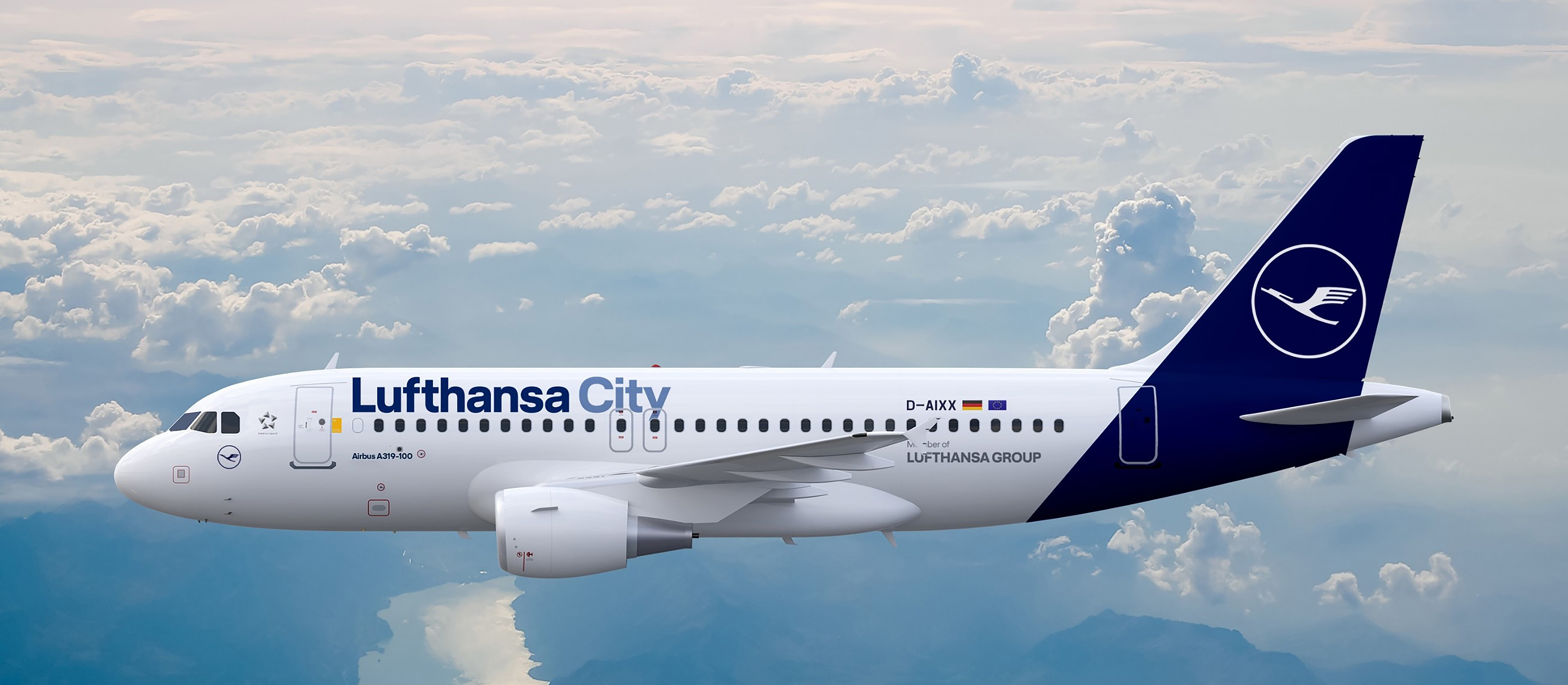 An Airbus A319-100 in flight above the clouds, photographed over a mountain landscape with lake