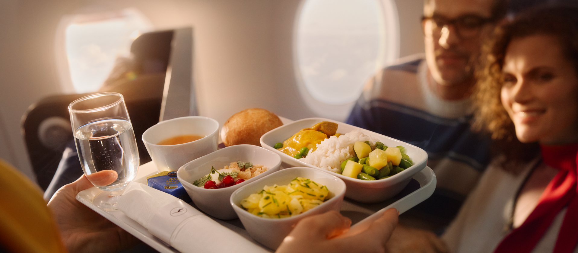 Eine Flugbegleiterin bringt einem Paar ein Menu
