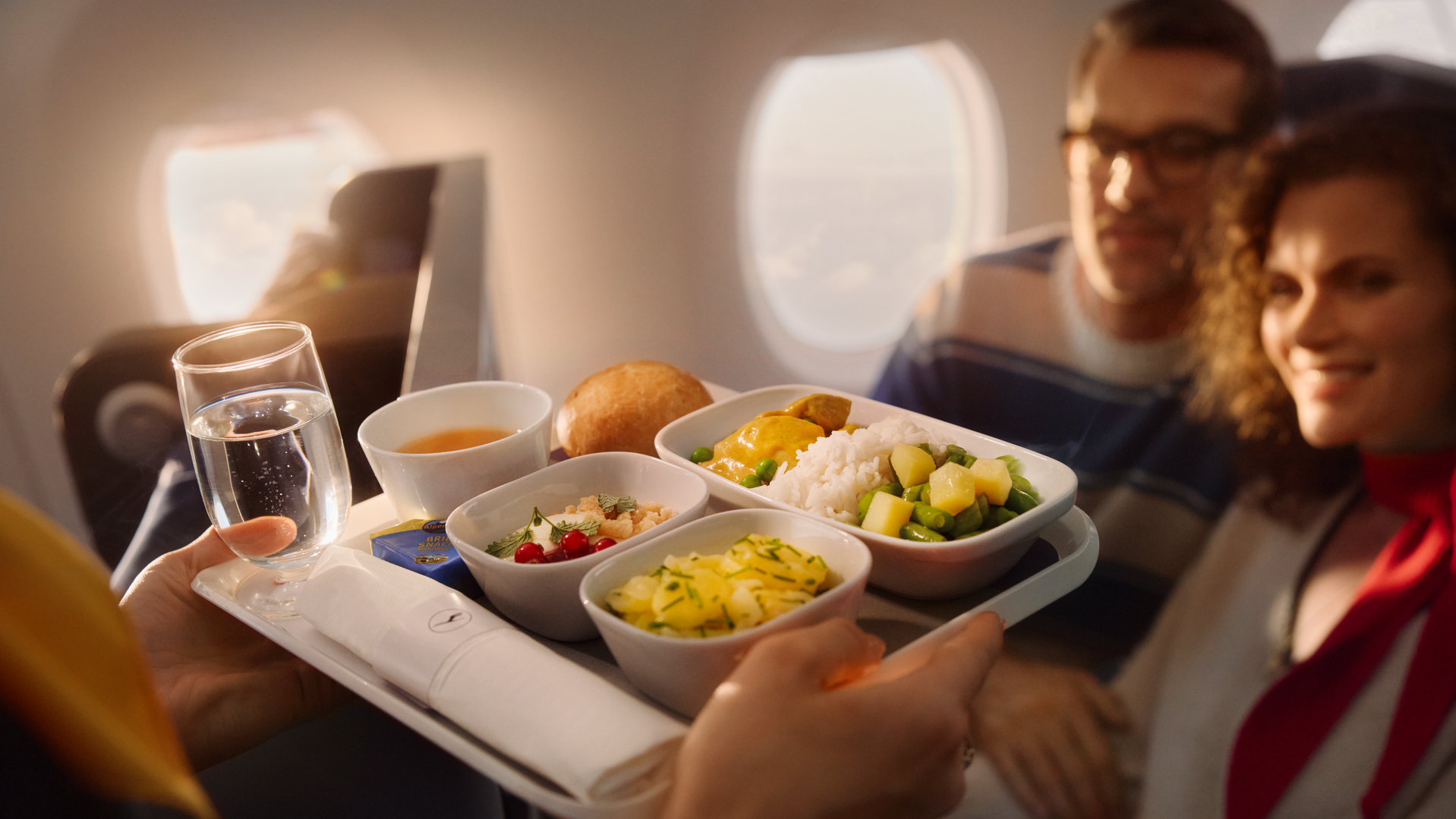 Eine Flugbegleiterin bringt einem Paar ein Menu