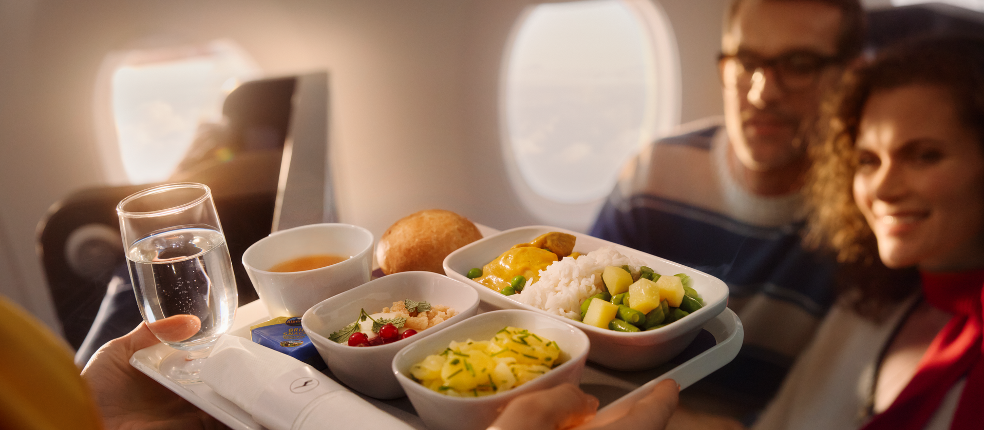 Eine Flugbegleiterin bringt einem Paar ein Menu