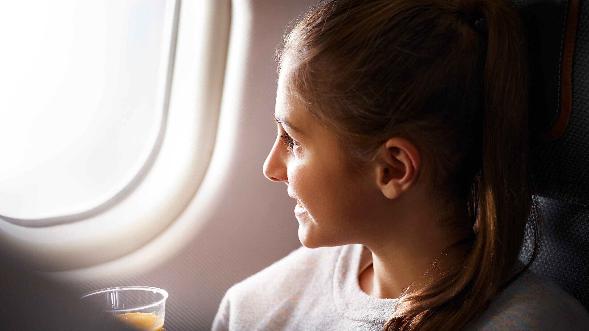 A child sits on a plane and looks outside